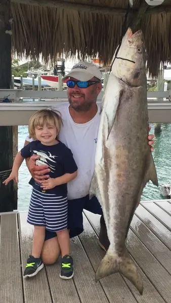 Little boy standing next to a big fish at Blowing Rocks Marina