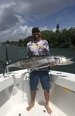 Angler with a kingfish in front of the Jupiter Lighthouse
