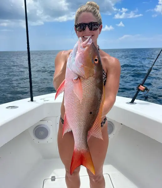 Angler holding a mutton snapper caught bottom fishing