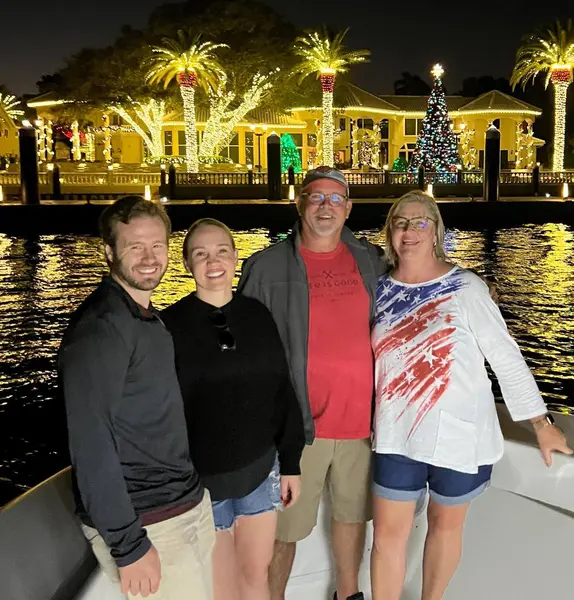 Family aboard Tom Cat at night with holiday lights along the Intracoastal