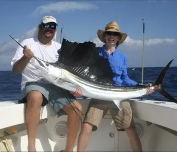 Couple holding a sailfish on the deck of the Tom Cat