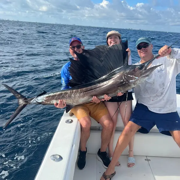 Three anglers hold up a sailfish for a photo before releasing it off Jupiter