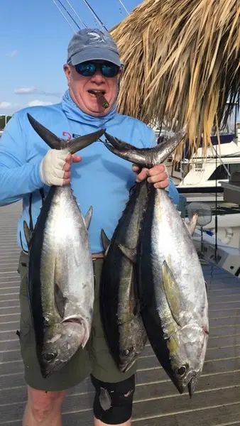 Angler at the dock holding two tuna