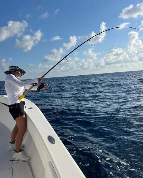 Woman fighting a fish from the bow of the boat on a sunny day
